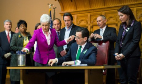 A photograph of Gov. Dannel P. Malloy signing the bill passed in response to the Newtown shootings, surrounded by family members of Sandy Hook Elementary School children who were killed.