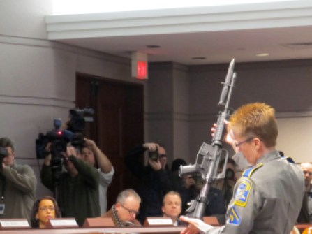 A state trooper displays a banned AR-15 for legislators during a hearing in 2013