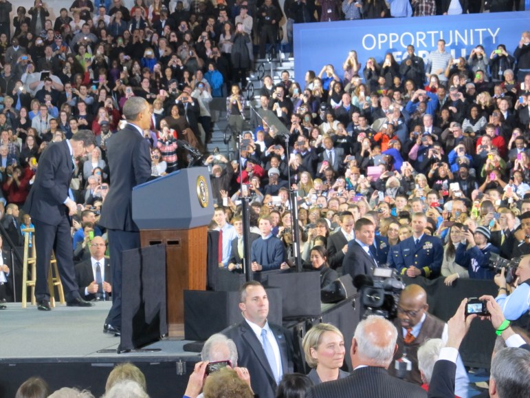 Obama gestures to students in the bleachers in front of some White House stagecraft: A sign saying, "Opportunity for All."