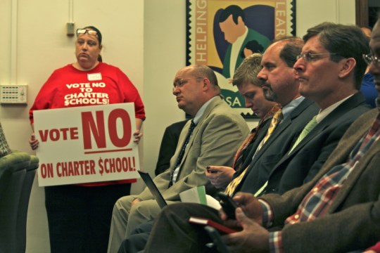A parent from Bridgeport holds up a sign in opposition to additional charter schools opening in her community