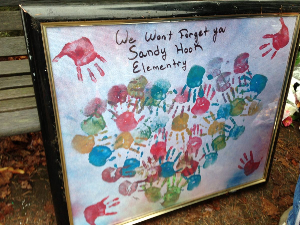 A sign with painted handprints on it, with words that read: "We won't forget you Sandy Hook Elementary."