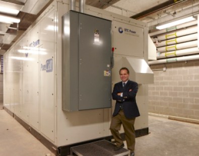 Bruce Becker stands beside the fuel cell that can supply most of the electricity needed to power his building at 360 State St. in New Haven. The fuel cell runs at half power because regulators have yet to decide whether he can sell power to residents of his 500 apartments. 