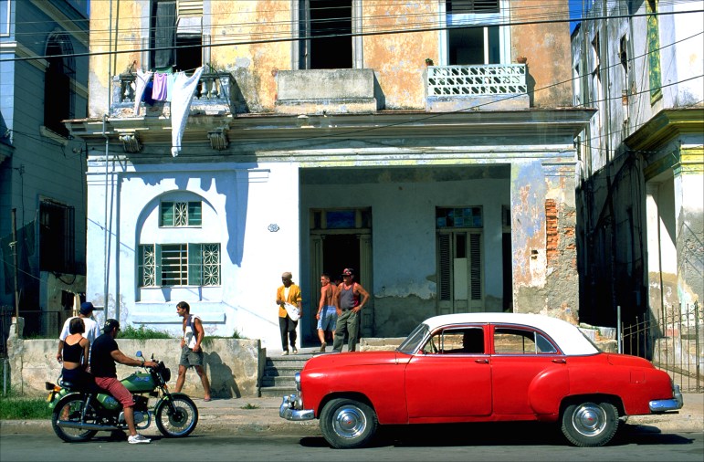 A vintage early 1950s Chevrolet adds some color to an otherwise drab, crumbling apartment building in Havana’s Vedado neighborhood.