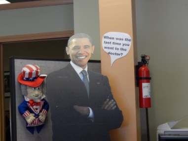"When was the last time you went to the doctor?" a speech bubble next to a cardboard cutout of the president read inside a Hartford insurance and tax office that advertised helping people sign up for Obamacare.