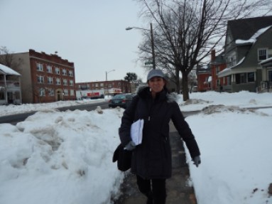 Marta Persia walks down Wethersfield Avenue in Hartford, hoping to find people who are uninsured and hang up flyers advertising help getting coverage.