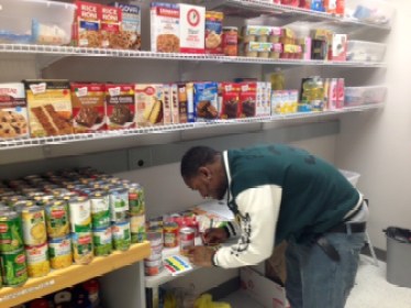 Jonas Labaze of Norwalk, a volunteer at the Norwalk Community College food pantry, places expiration-date labels on food items.