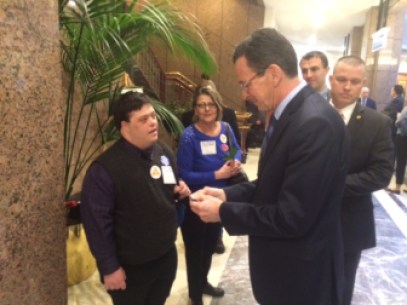 Zeb Olko gives Gov. Dannel P. Malloy his card. Olko, who has an intellectual disability,  was the Legislatie Office Building to ask that funding be restored to the Department of Developmental Services.