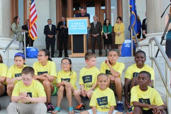 The leader of one of the state's teachers' unions flanked by Republican and Democratic legislators