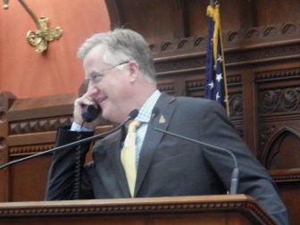 Speaker Brendan Sharkey on the phone from the House podium as the chamber debates budget adjustments late Monday.