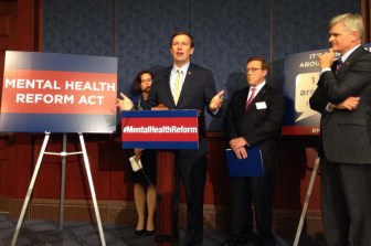 Sen. Chris Murphy, at podium, with Sen. Bill Cassidy, right, and Mary Gilberti at rear.