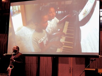 A video of Ana Grace and Isaiah Márquez-Greene playing piano and singing played at the beginning of the conference after their father, musician and professor Jimmy Greene, played.
