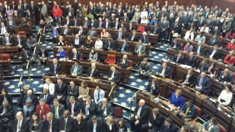 State Senators watch the governor's speech. One chair is empty.