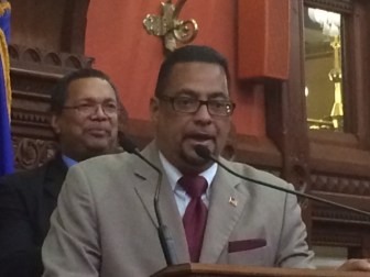 Geraldo Reyes, Jr. briefly addresses the House. Larry Butler, a colleague from Waterbury, watches.