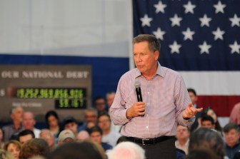 Republican presidential candidate John Kasich speaks at Glastonbury High School Friday with his traveling national debt clock running behind him.