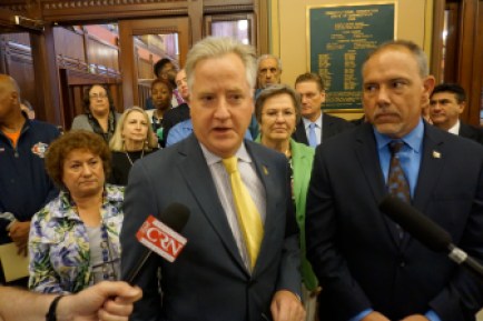 House Speaker J. Brendan Sharkey briefs reporters as his caucus members stand by.