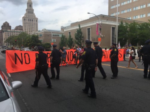 Hartford police officers approach a protester holding a banner that block a portion of Main Street Monday.