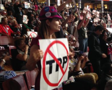 Connecticut Sanders delegate Mercedes Alonso holds up a sign opposing the Trans-Pacific partnership trade pact on the first day of the convention.