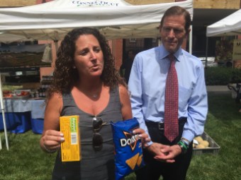 Tara Cook-Littman, left, and U.S. Sen. Richard Blumenthal, right. Cook-Littman is holding two products with GMO labels.