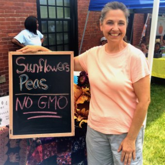 Rebecca Salva, co-founder of Bioessential Greens, LLC in Hartford, holds up a sign telling customers her products have no GMOs.
