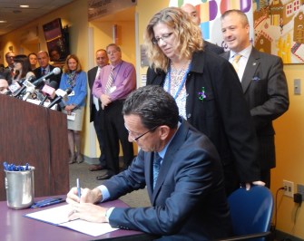 Gov. Dannel P. Malloy ceremonially signs the bill legalizing the use of medical marijuana for minors. Behind him is Susan Meehan and Consumer Protection Commissioner Jonathan Harris.