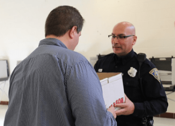 Officer Vic Fuentes delivers needed ballots to Moderator Ryan Munden at Wilbur Cross High School.