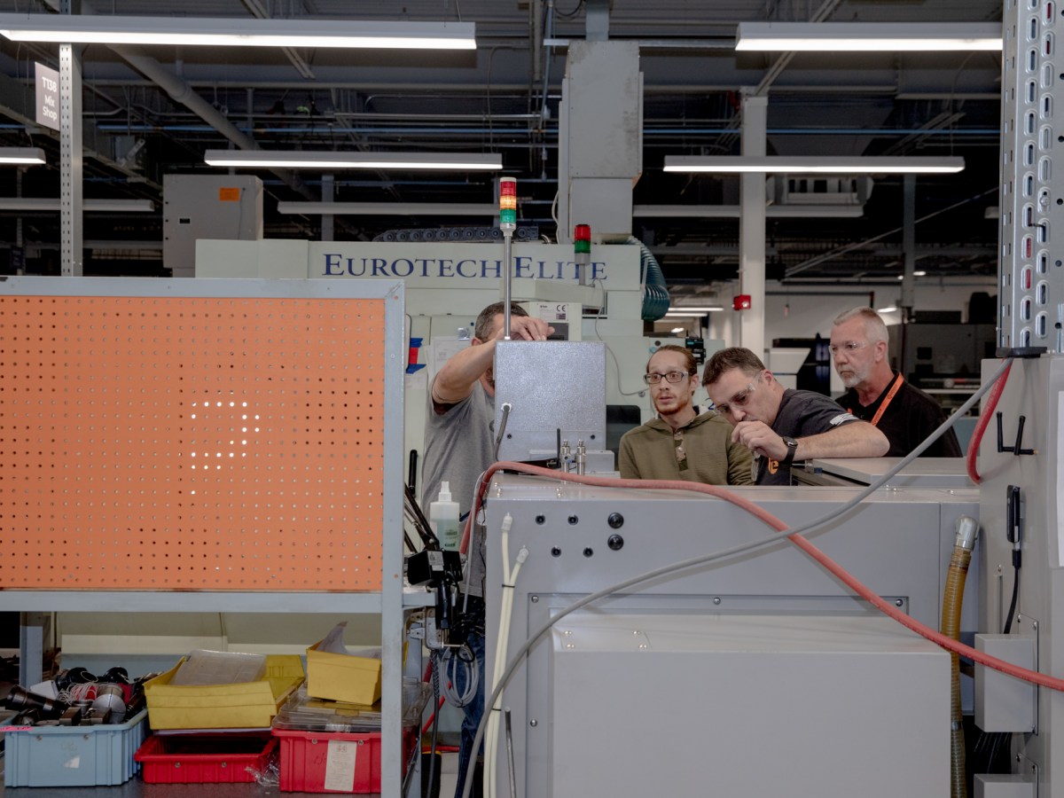 Several skilled manufacturing workers meet on a shop floor.