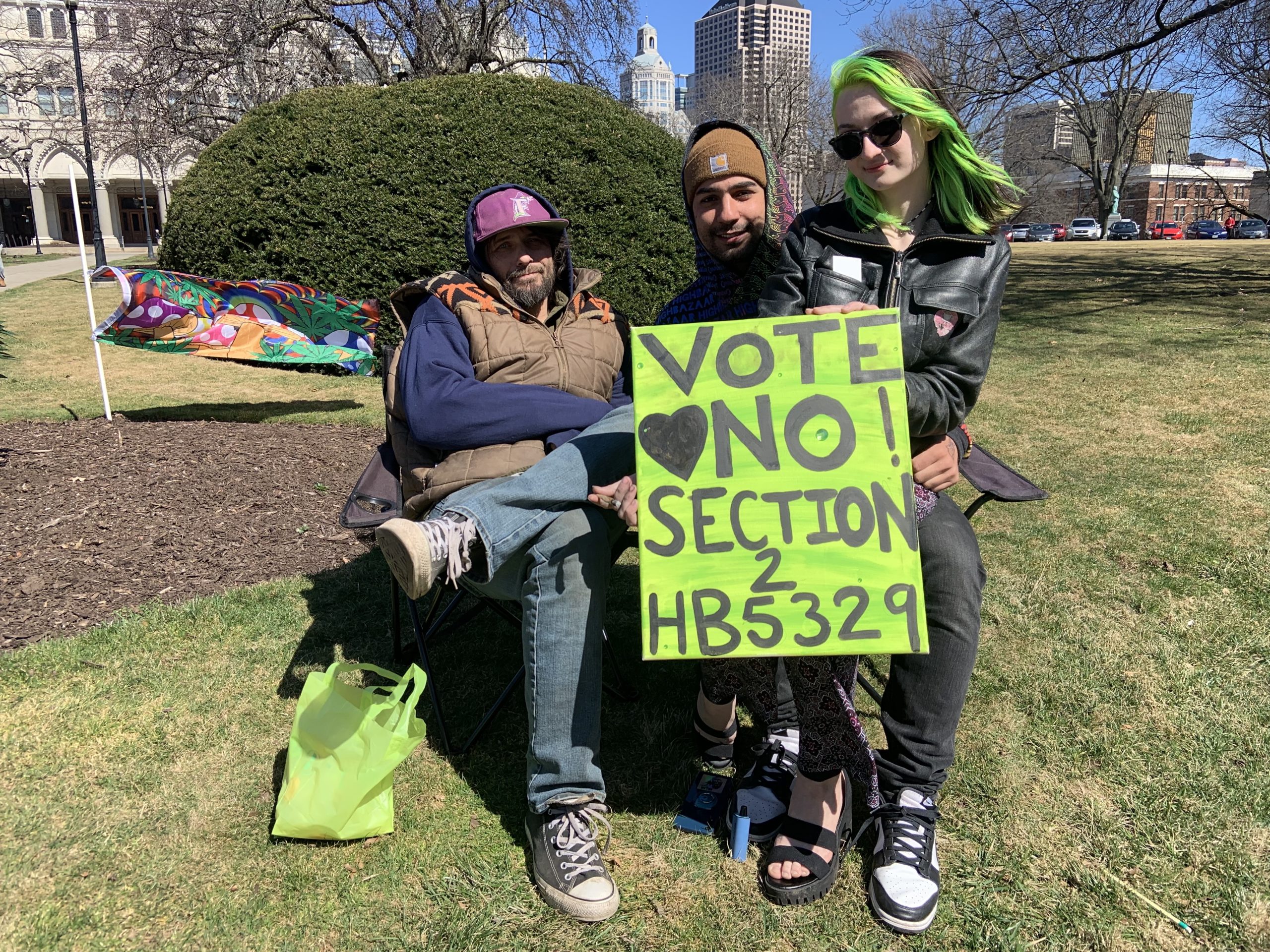Kelly Crain, of Middletown, Aldo Cucciniello, of Hamden, and Joshua Frazer, of East Hartford sit in front of the state Capitol on Tuesday, March 22, 2022. The three were part of a protest against a bill that would ban cannabis gifting in Connecticut. Crain and Frazer are medical marijuana patients and said they've needed to get their medicine as gifts from friends or family members at times when their symptoms were particularly bad.