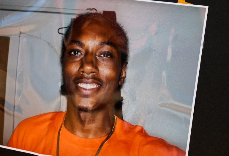 Randy Cox, a Black man smiling with an orange shirt and gold chain on, smiles for a photo.