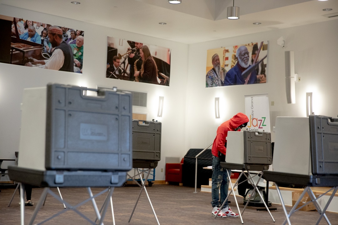 Una persona con una roja vota en un colegio electoral vacío.