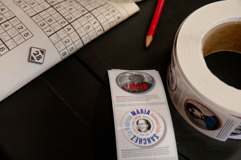 Calcomanías de mujeres de Connecticut que contribuyeron a ganar los derechos del voto en sima de una mesa con un lápiz y un sudoku.