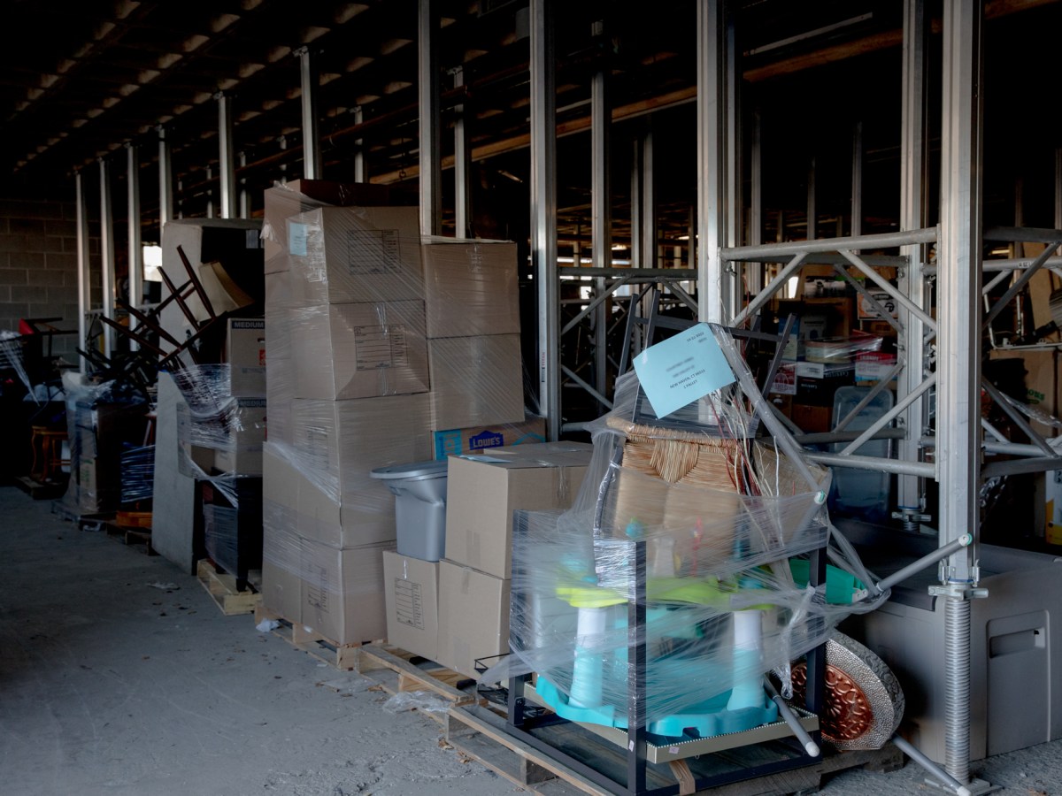 Boxes and furniture sit on wooden pallets in a warehouse.