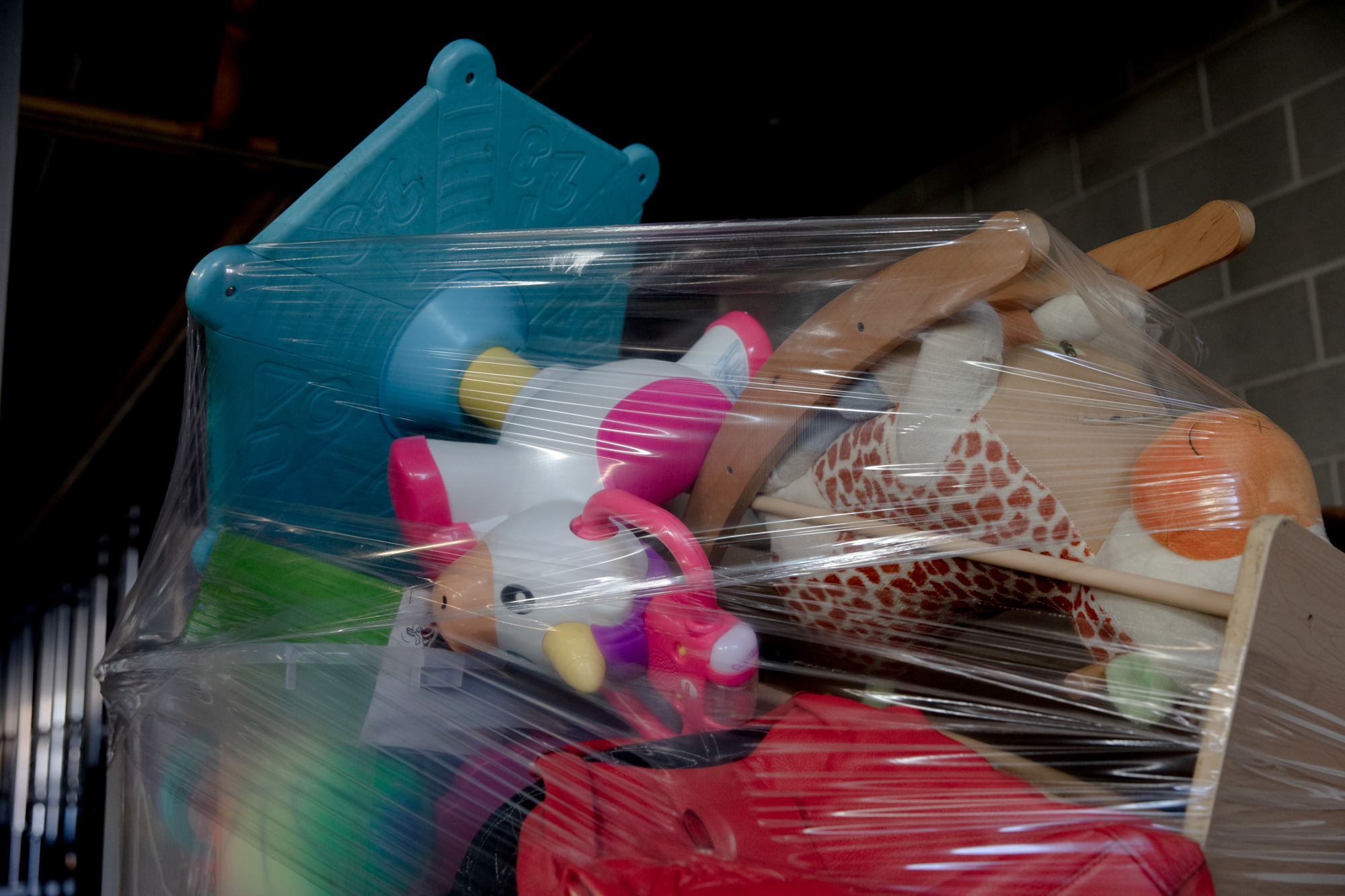 A toy cow and rocking horse are wrapped together in plastic.