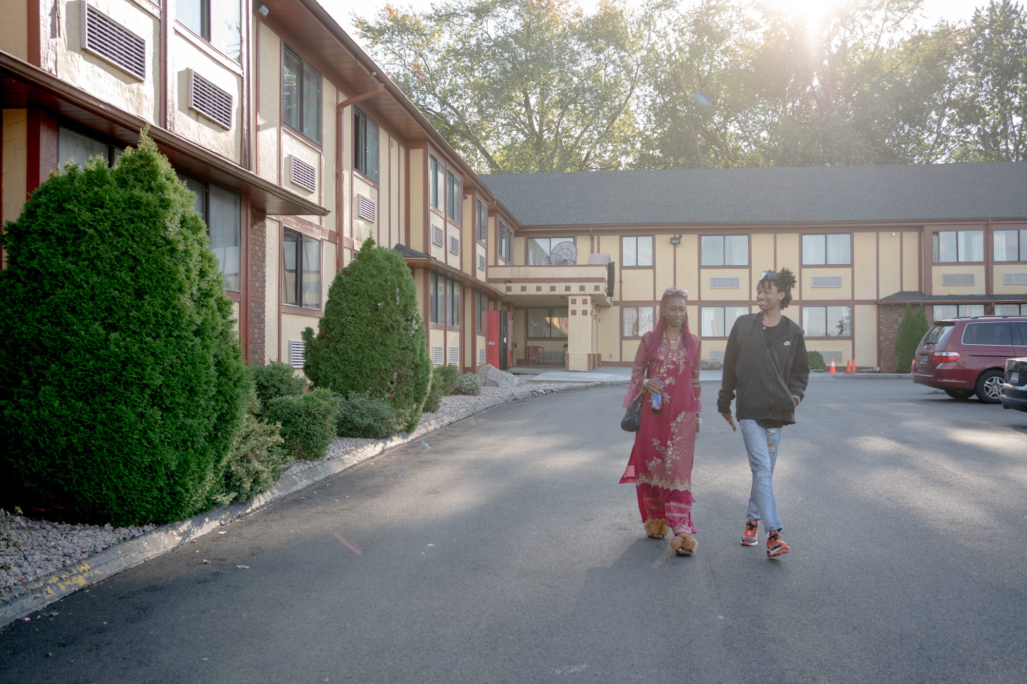 A woman and her son walk in the parking lot of a motel.