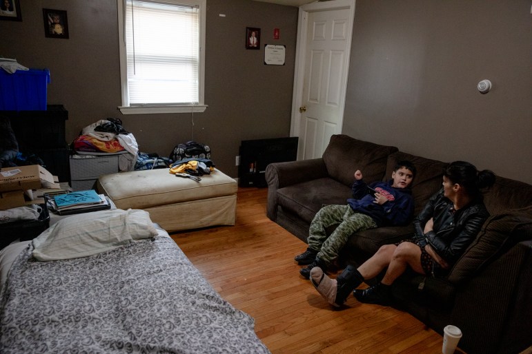 A boy and his mother sit on a living room couch.