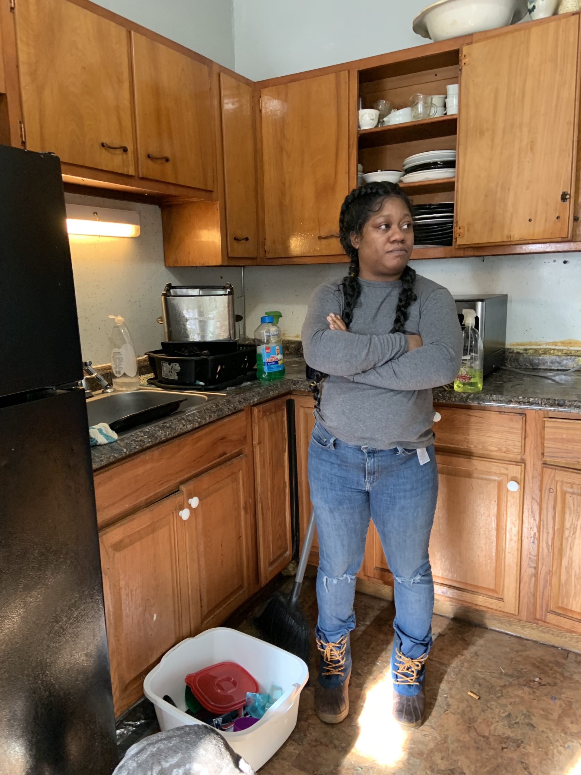 A woman stands in an apartment kitchen.
