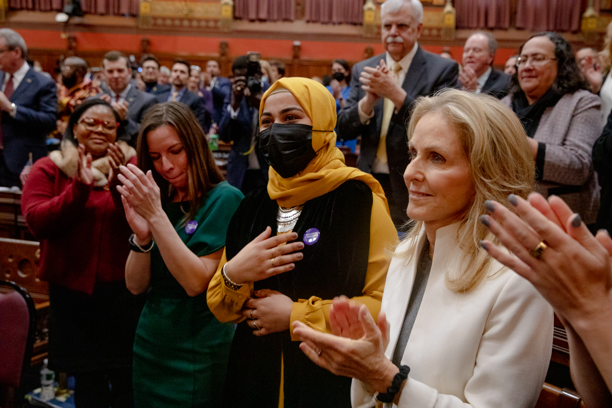 La gente ovaciona a Sara Niazai, quien se mudó a Connecticut desde Afganistán en 2020, mientras el Gobernador Lamont la presenta y le da la bienvenida por hacer del Estado su hogar. Niazai dijo que se siente apoyada y aprecia su mensaje de que recibirá una educación que no pudo obtener en Afganistán. La Primera Dama Annie Lamont está a la derecha.