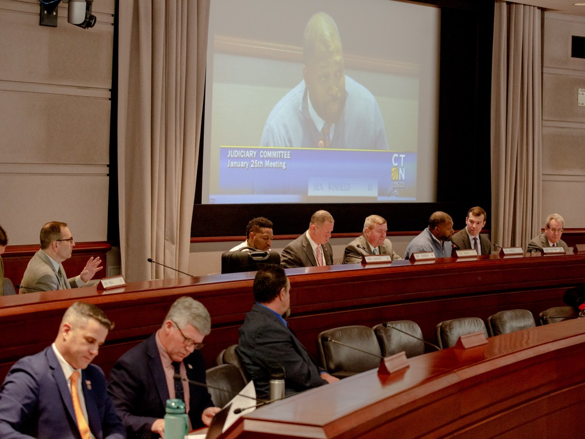 A room full of lawmakers in the Legislative Office Building of Hartford. Sen. Gary Winfield of New Haven is seen a projector at the front of the room.