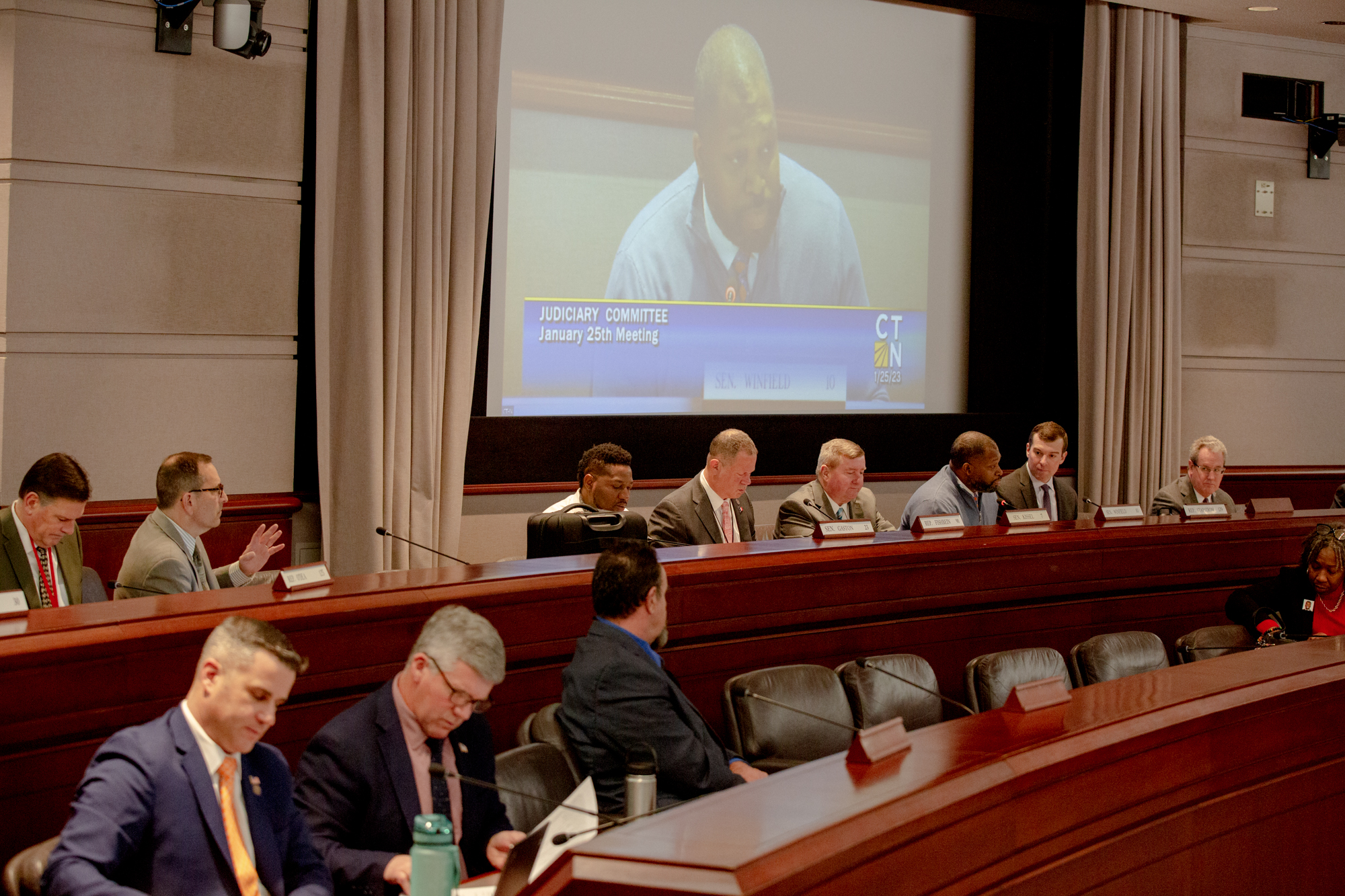 A room full of lawmakers in the Legislative Office Building of Hartford. Sen. Gary Winfield of New Haven is seen a projector at the front of the room.