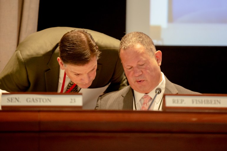 Rep. Tom O'Dea is seen looking over the shoulder of Rep. Craig Fishbein while the two are in a Judiciary Committee meeting. The two appear to be looking down at something.