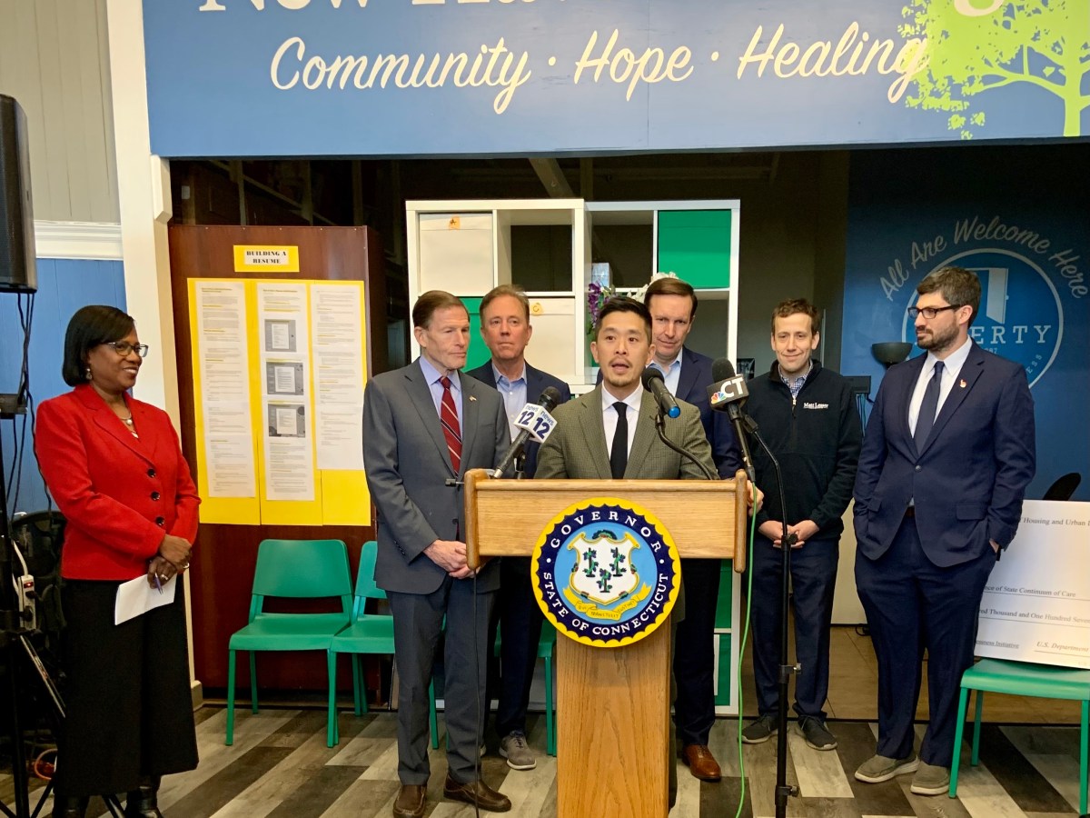 A man speaks at a podium with several other men standing behind him.