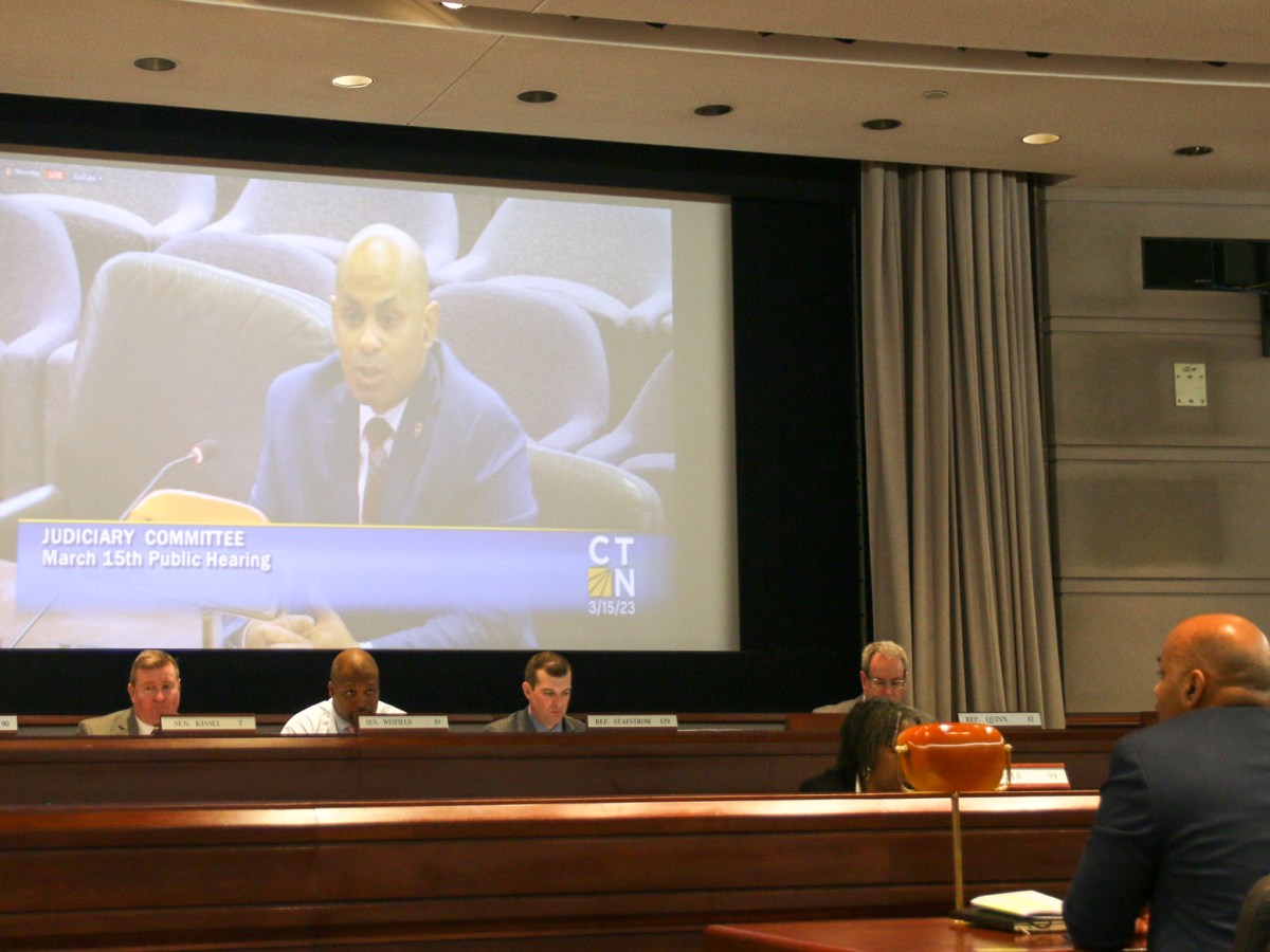 Angel Quiros, Connecticut's Department of Correction Commissioner, is seen on a projector in a room with lawmakers.