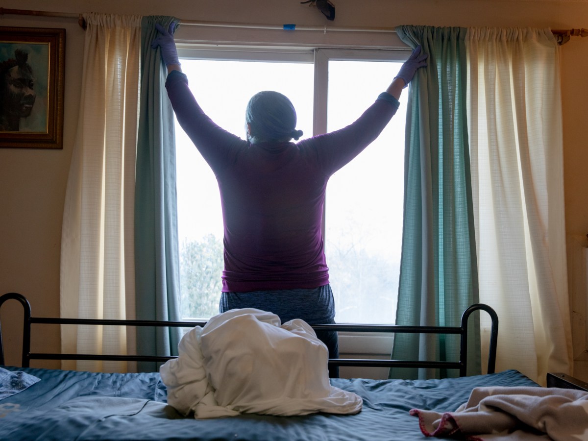 Michele May-Javeed abre las cortinas para empezar el día en casa de su hermano. “Estamos luchando por llegar a un salario a $20”, dijo. "Por la simple dignidad de recibir el salario que merecemos".