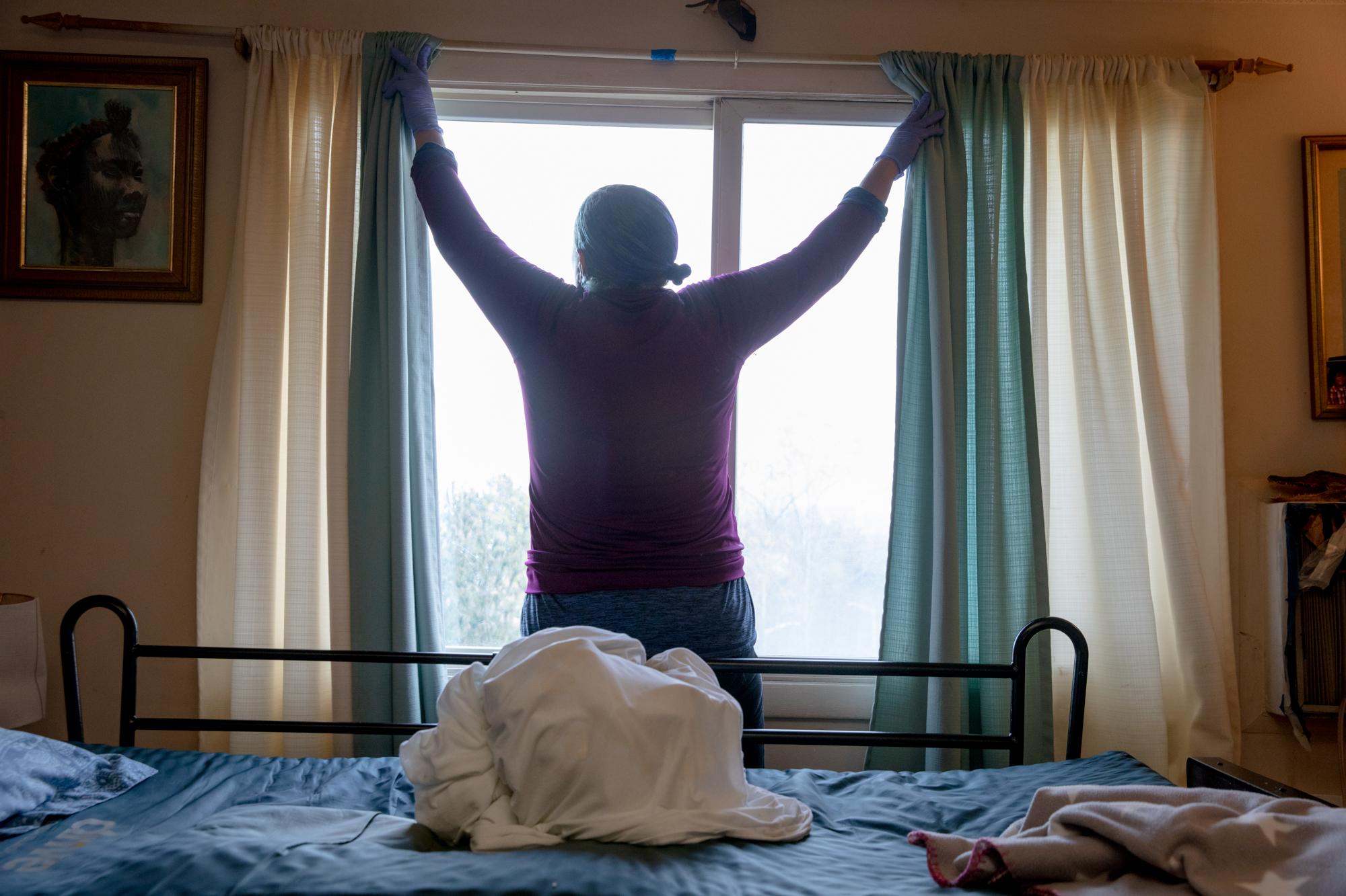 Michele May-Javeed abre las cortinas para empezar el día en casa de su hermano. “Estamos luchando por llegar a un salario a $20”, dijo. "Por la simple dignidad de recibir el salario que merecemos".