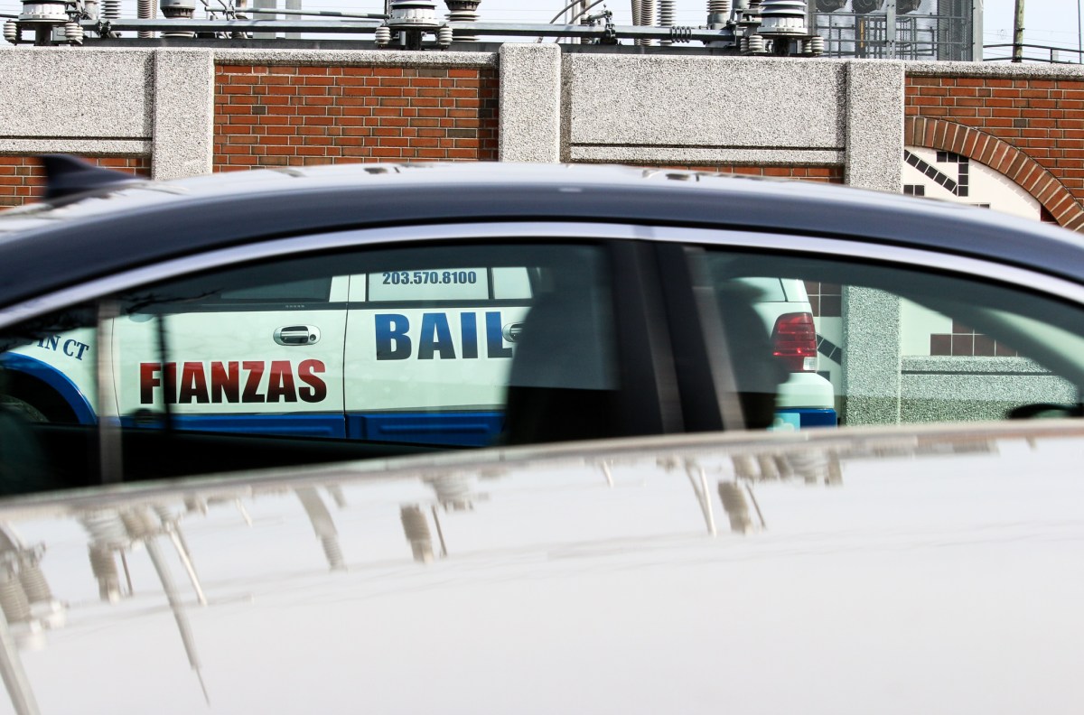 A car drives past a parked white truck belonging to a bail bonds agency.