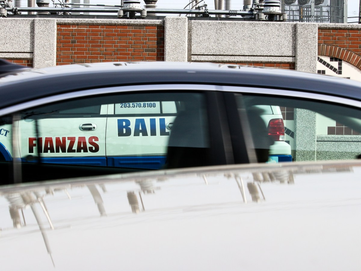 A car drives past a parked white truck belonging to a bail bonds agency.