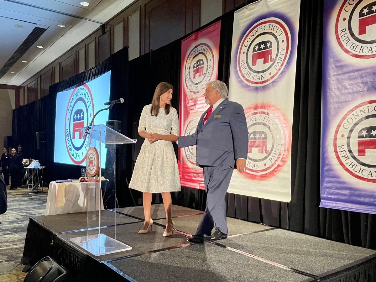 Two people shake hands on a stage.