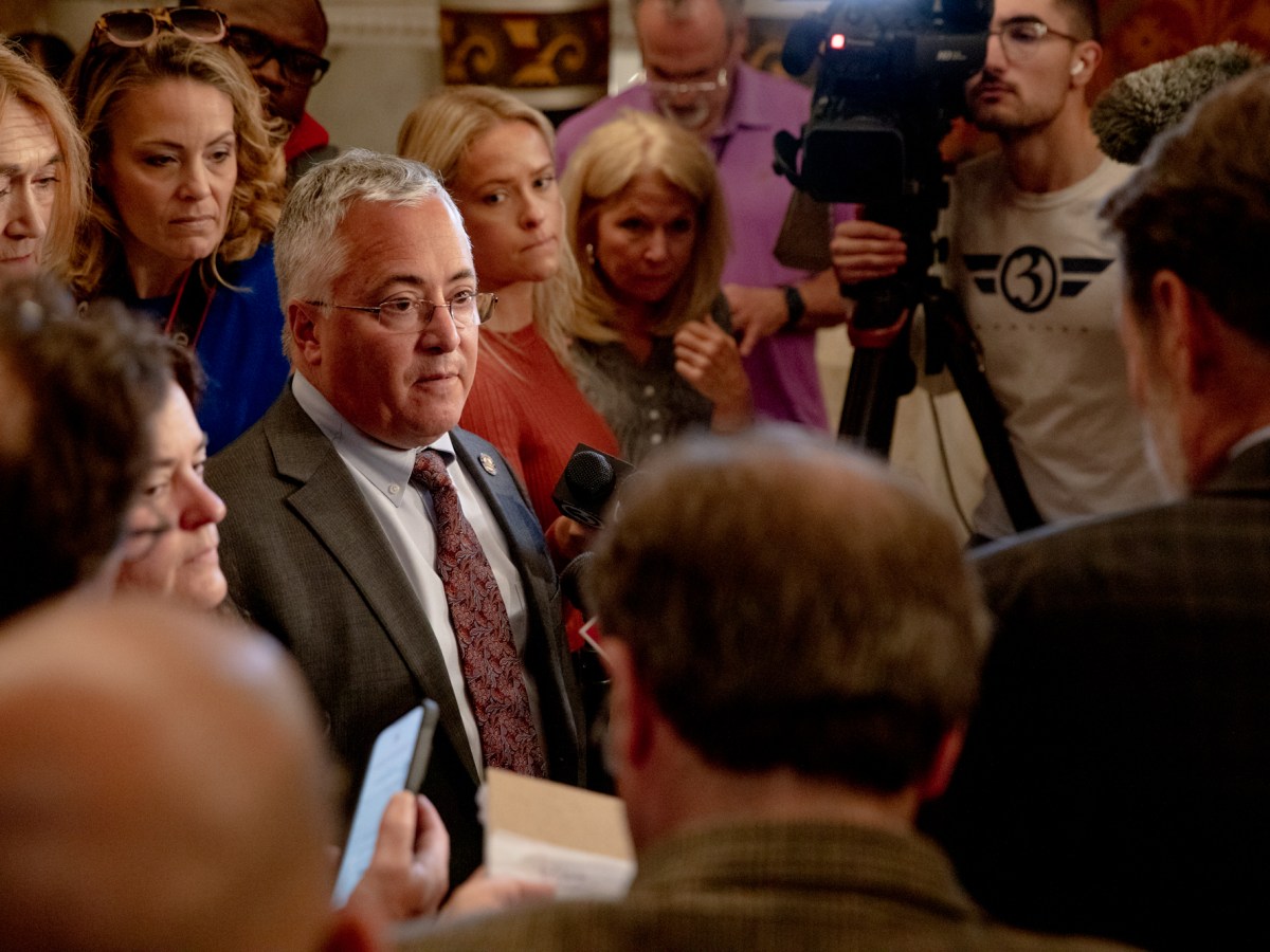 House Minority Leader Vincent J. Candelora is surrounded by Republican legislators and members of the press in a hallway at the state Capitol.