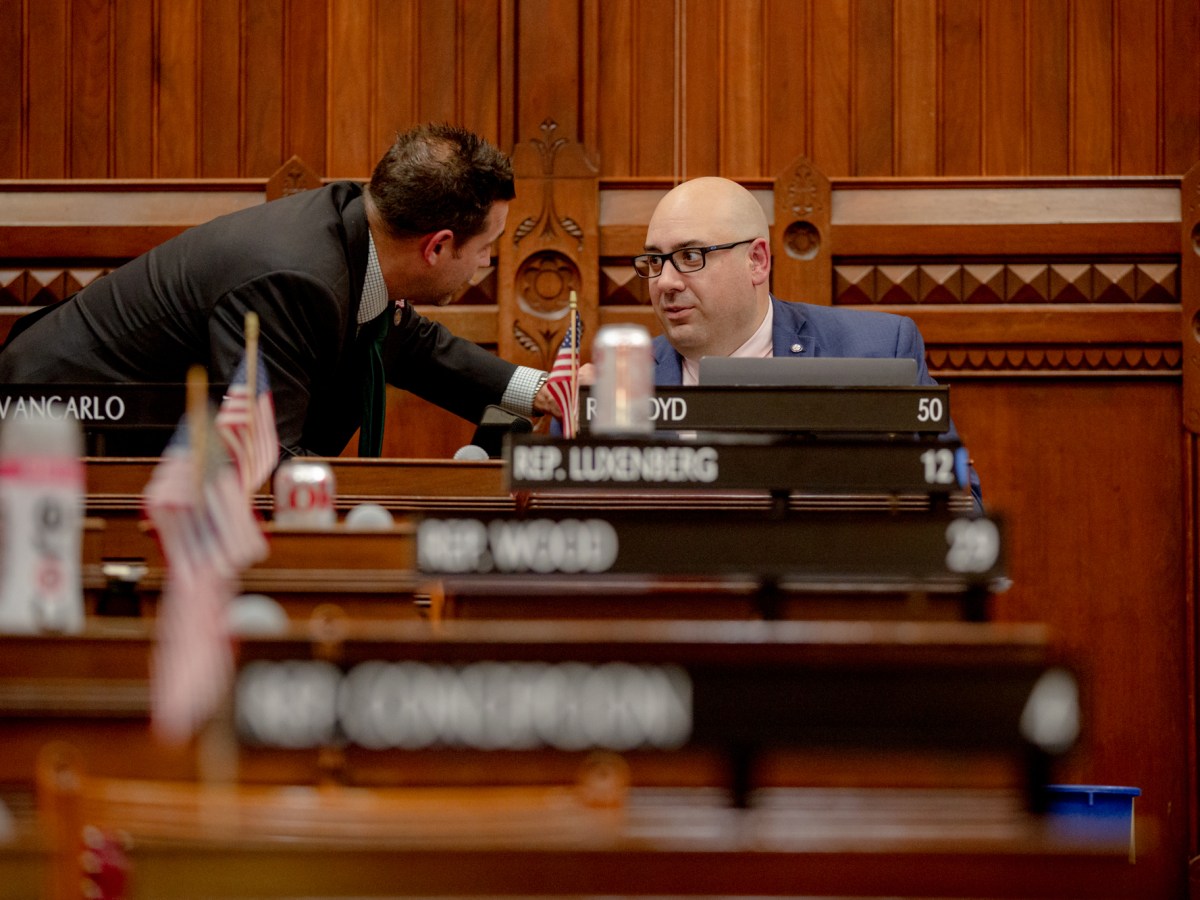 Rep. Pat Boyd is seen in the Connecticut House of Representatives chamber conversing with another legislator.