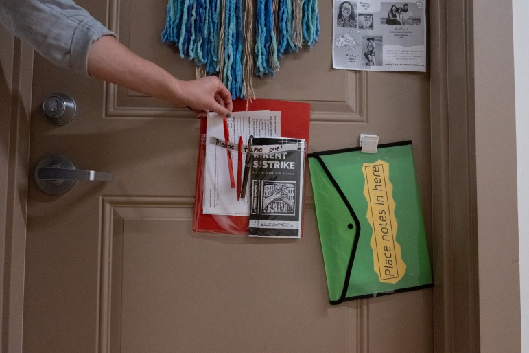 A hand picks up a flyer from a neighbor's door at Cargill Falls Mill in Putnam, CT. Both she and her neighbor are part of the tenants' union protesting poor living conditions.