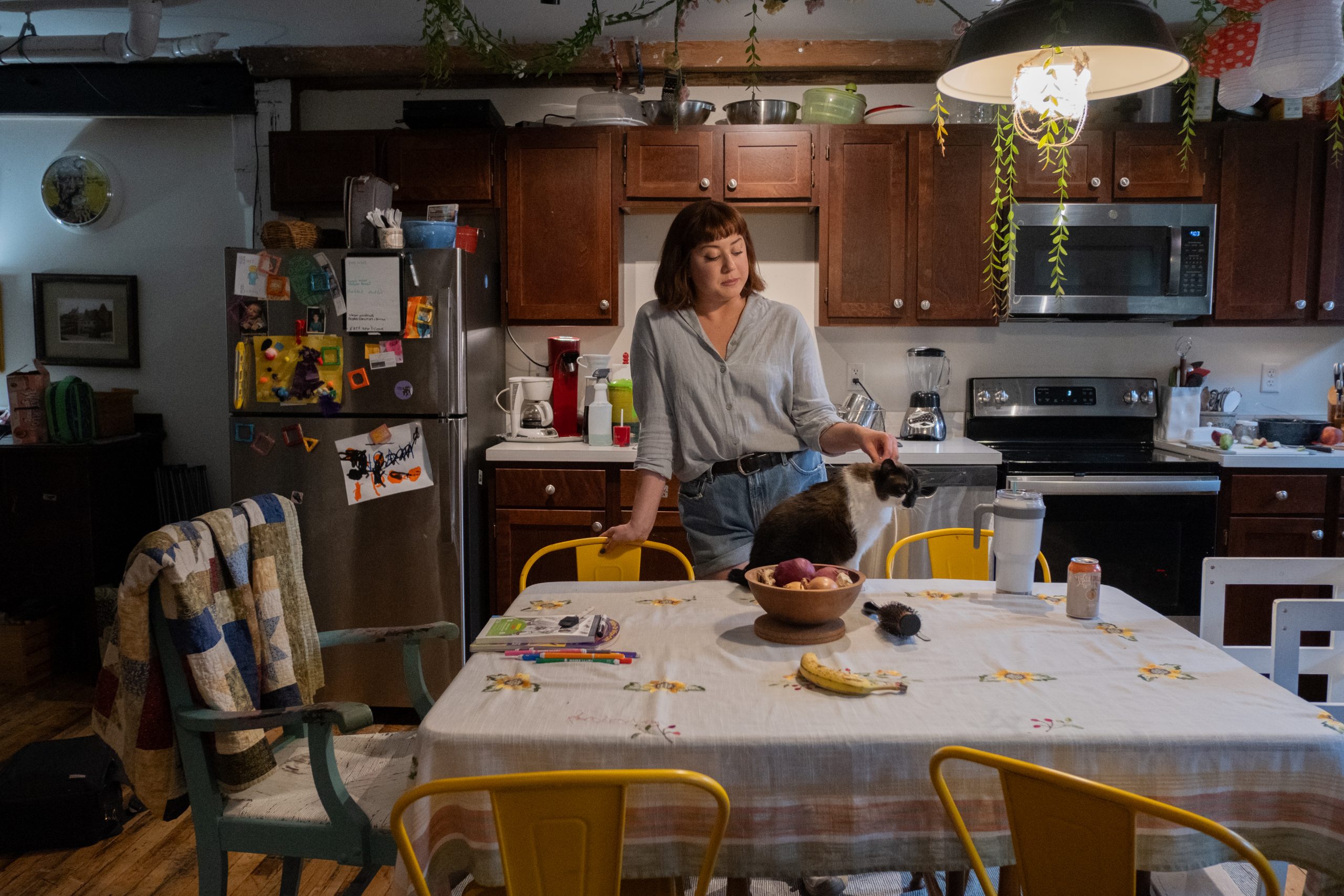 A woman stands behind her kitchen table.